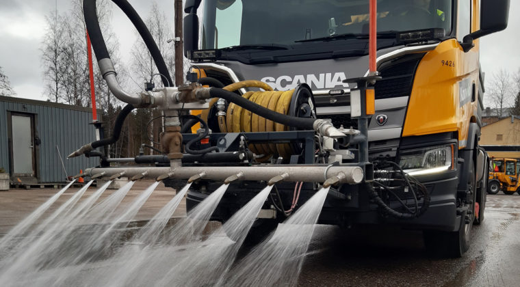 Kuorma-auto suihkuttaa vettä kadulle hiekan poistoa varten