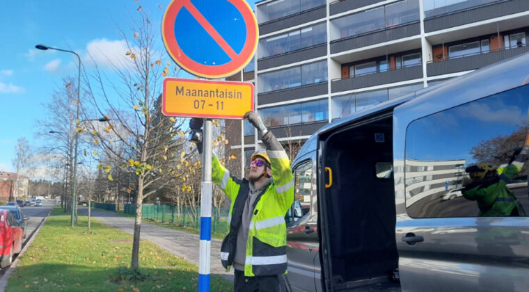 Työmies asentaa pysäköintikieltomerkkiä kadulla.